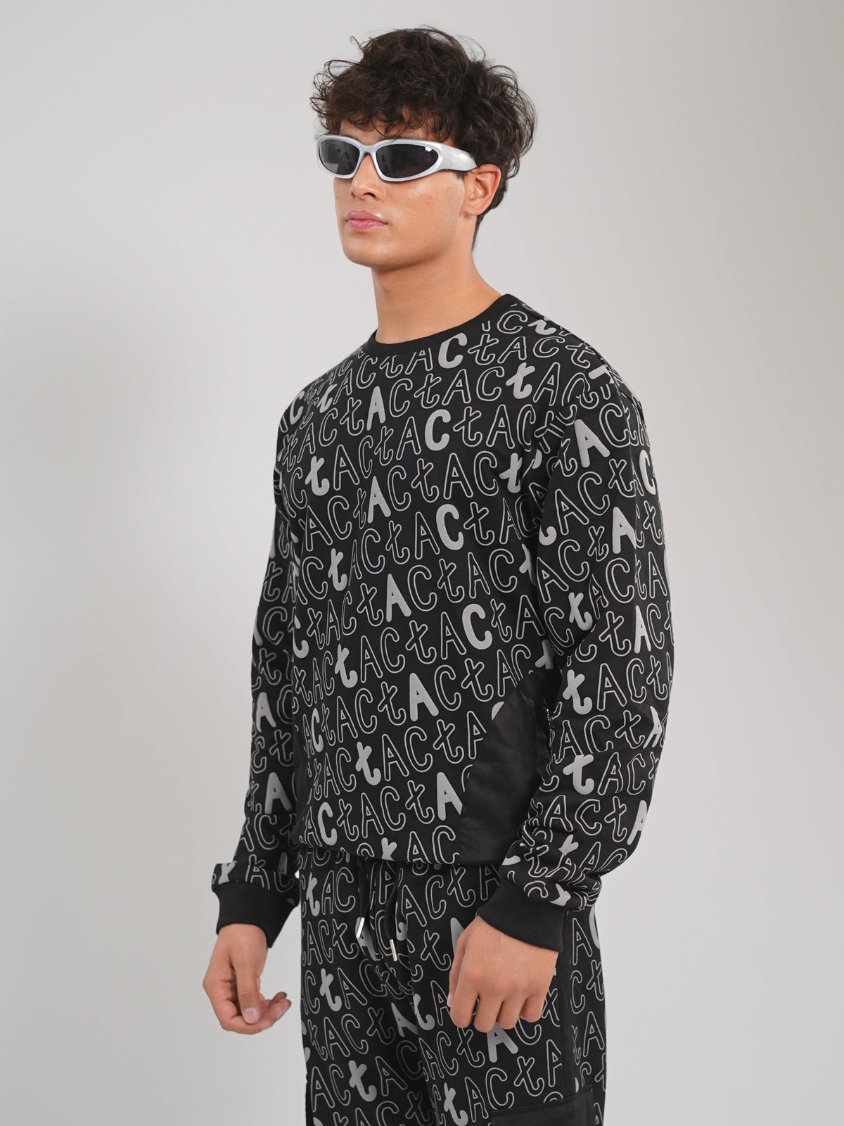 Person wearing a black sweatshirt with a pattern of letters on a gray background
