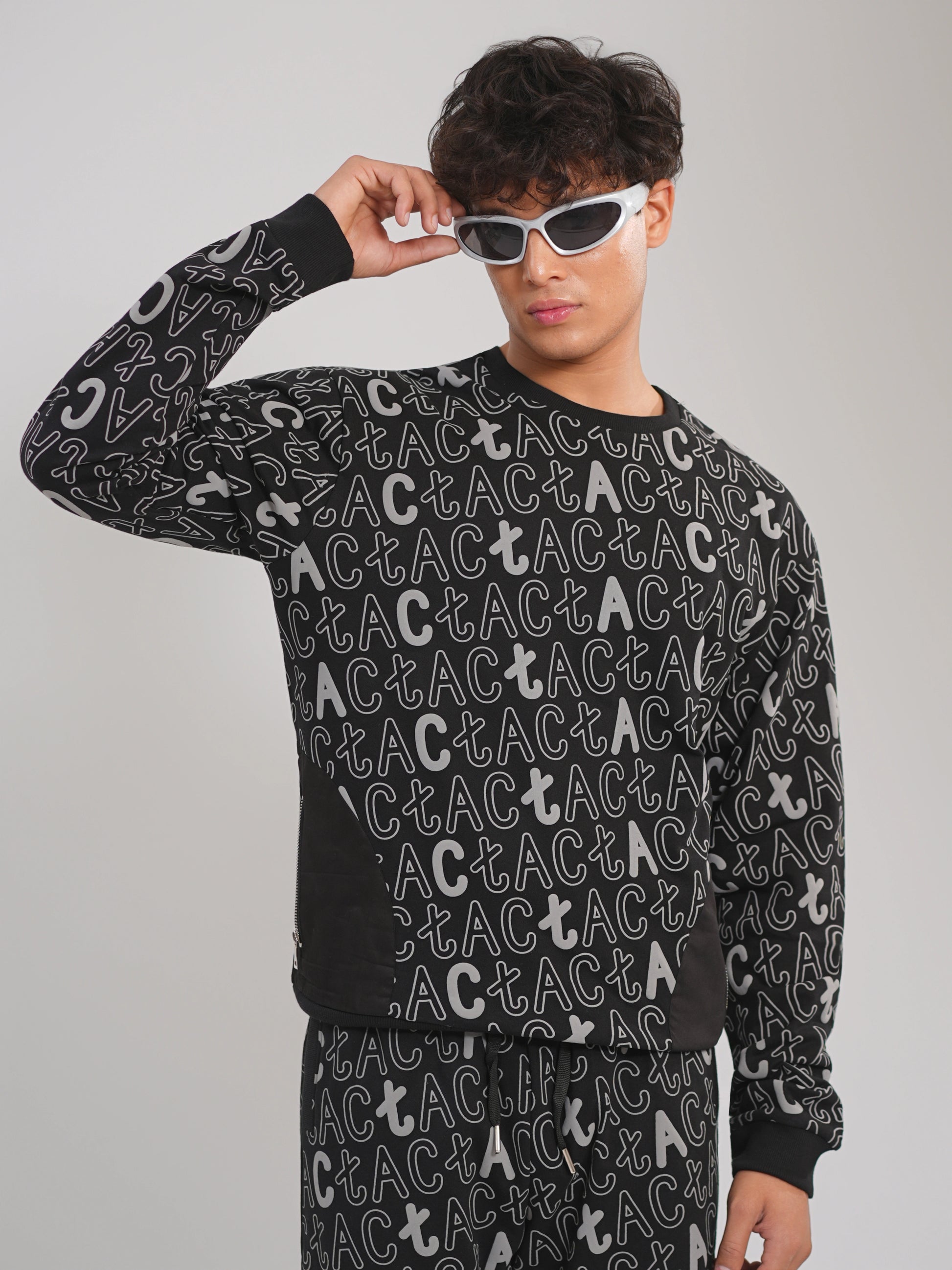 Person wearing a black sweater with white text pattern on a gray background