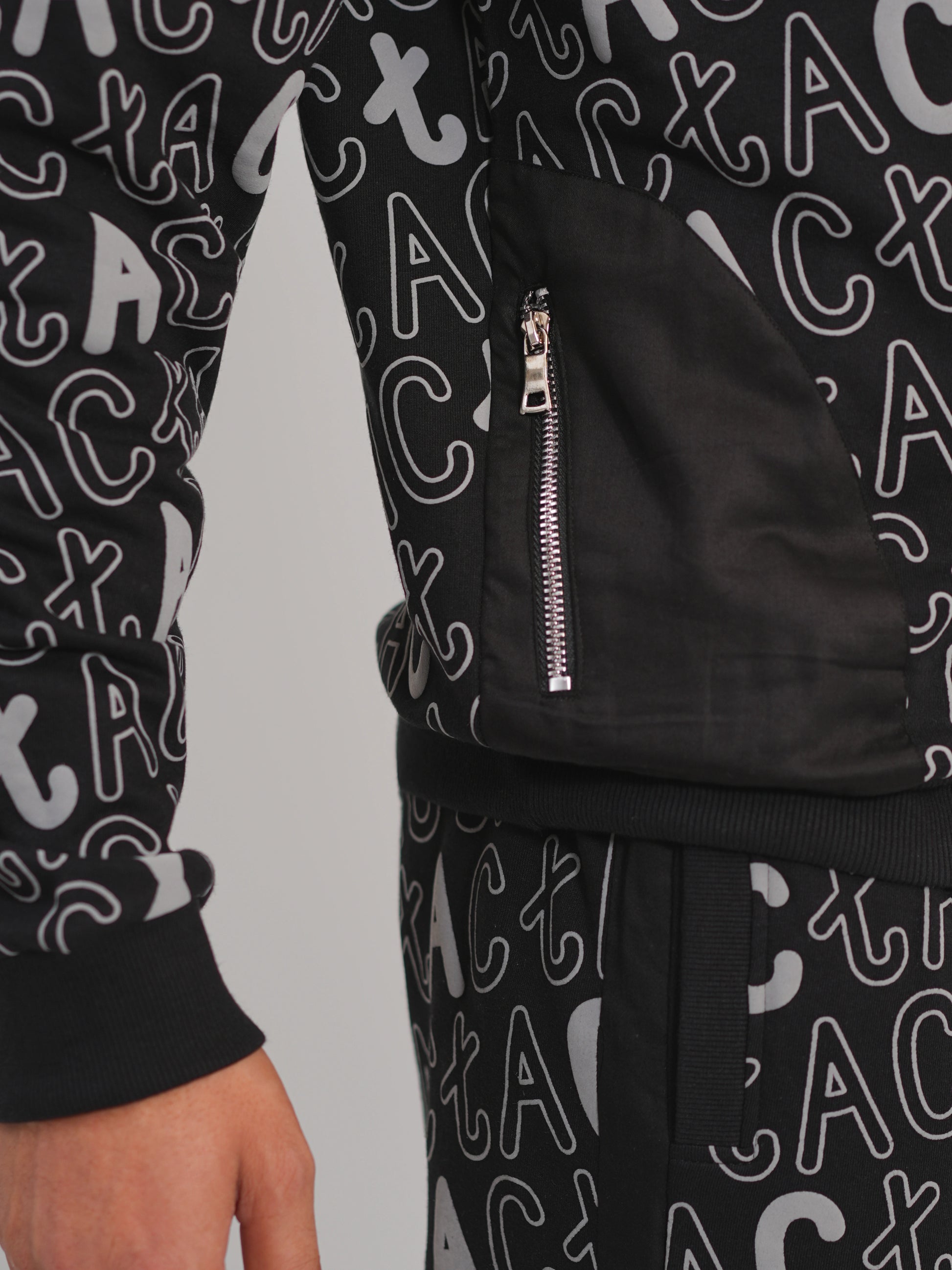 Black tracksuit with white lettering on a plain background