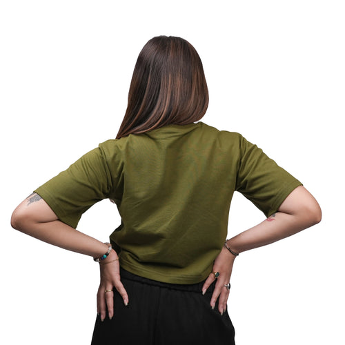 Person wearing a green shirt with hands on hips against a white background