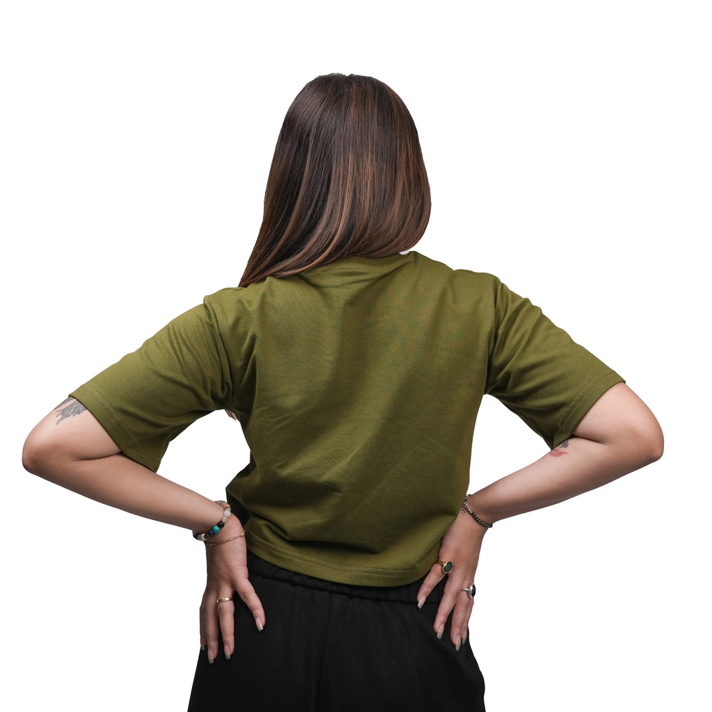 Person wearing a green shirt with hands on hips against a white background