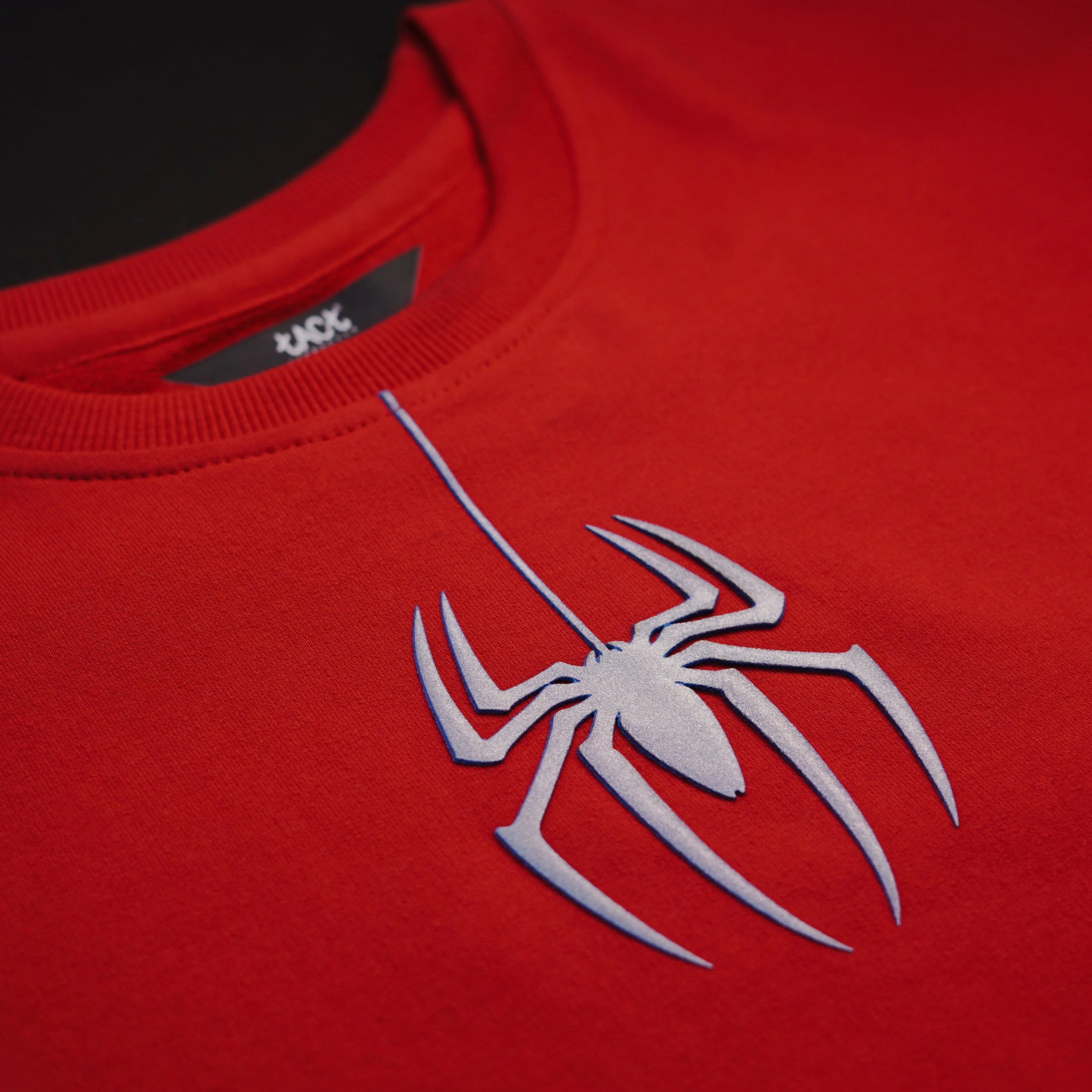Red shirt with a silver spider logo on a black background
